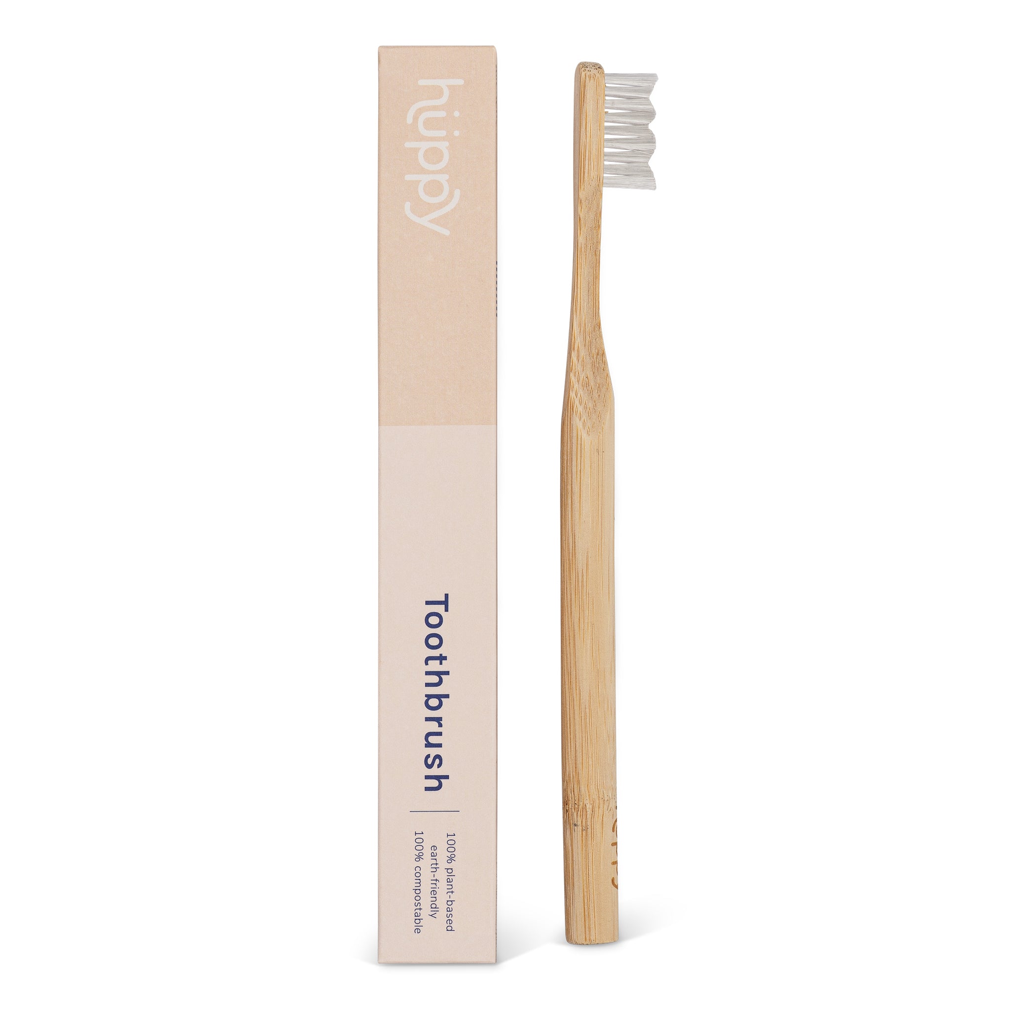 A bamboo toothbrush with white bristles, next to its packaging box which has a minimalist design and says Huppy.